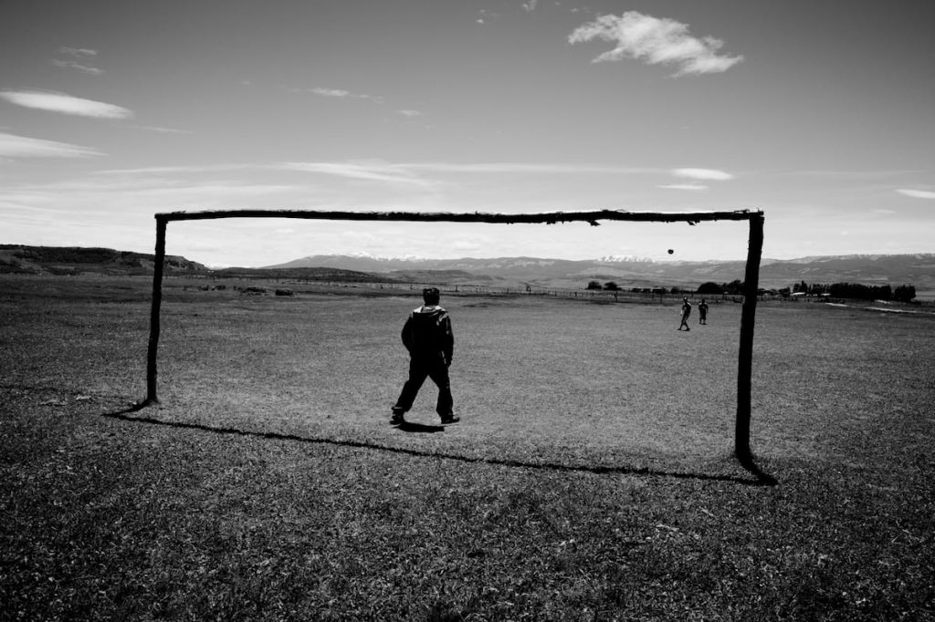 Black and white image of someone standing under a goalpoast